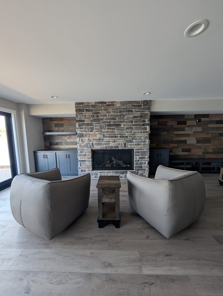 Lower-level family room with a stone fireplace and wood plank accent wall at The Lake House