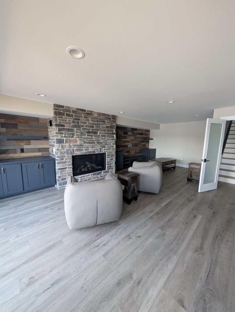Lower-level family room with stone fireplace and built-in cabinets at The Lake House