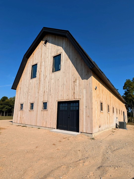 Finished exterior of The White Oak Barn with a gambrel roof and black carriage doors
